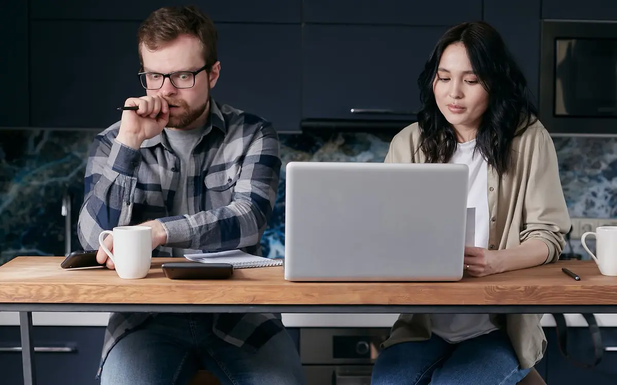 A couple planning together on a laptop at their kitchen table