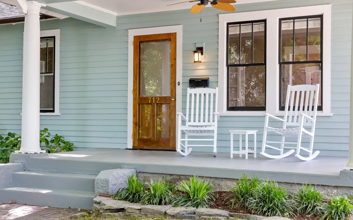 A front porch with white rocking chairs and a wooden door